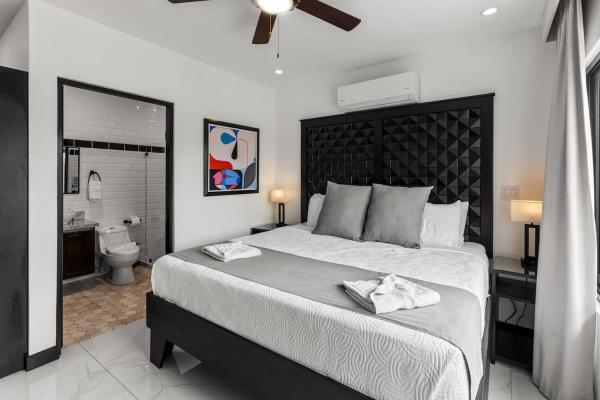1 King Bed Modern king bedroom with large tropical window view, bold accent headboard, and a private ensuite, luxury villa Jaco