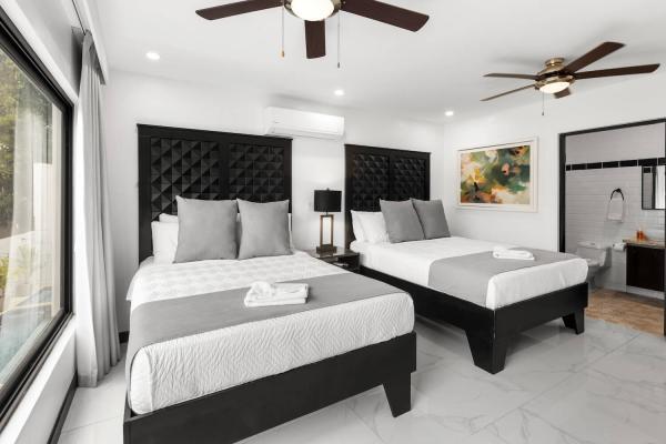 2 Queen Beds Luxurious king bedroom with bold tufted headboard, large windows, and a private ensuite bathroom at Villa Norma