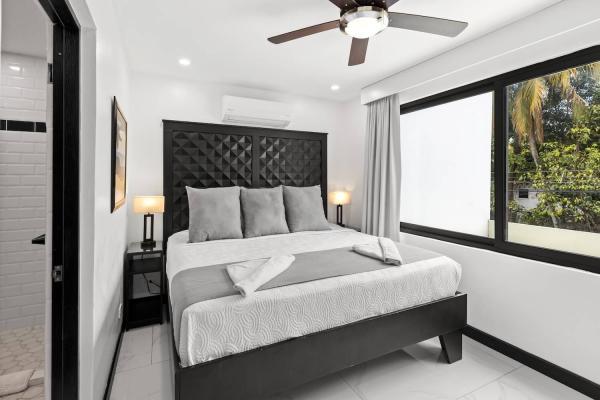 1 King Bed King bedroom with a statement tufted headboard, ceiling fan, and bright tropical rooftop views at Villa Norma
