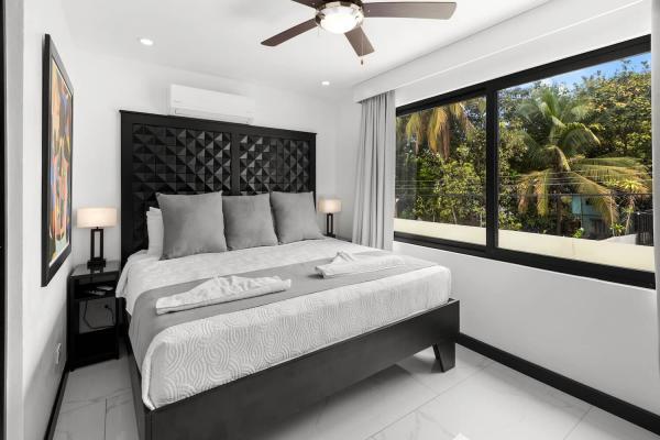 1 King Bed Bright king bedroom with tropical palm views through large windows at this Jaco Beach luxury vacation rental villa