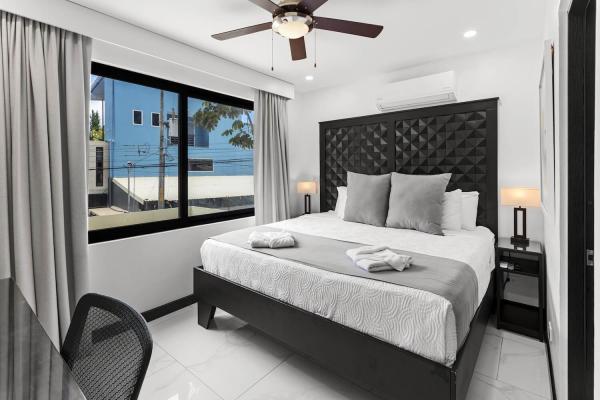 1 King Bed Modern king bedroom with large window, tufted headboard, and lush tropical garden views at Villa Norma Jaco