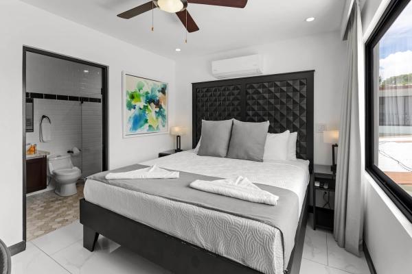 1 King Bed Sophisticated king bedroom with floor-length curtains, bold tufted headboard, and ceiling fan at Jaco Beach