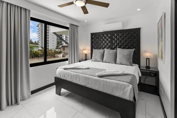 1 King Bed Bright corner king bedroom with dual windows, ceiling fan, and bold tufted headboard at Villa Norma Jaco