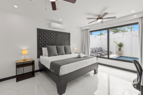 King bed with direct private pool view through sliding glass doors and sun loungers visible, Jaco Beach