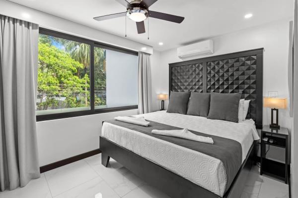 King bedroom with a large window framing a sweeping tropical palm tree view, central Jaco