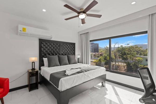 King bedroom with mountain and town views, red accent chair and ensuite bathroom access, Jaco Beach