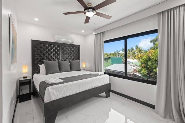 King bedroom with a large picture window framing the private pool and sun loungers below, Jaco Beach