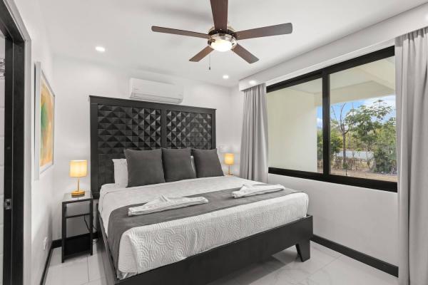 King bed positioned to enjoy the private pool view through sliding glass doors with sun loungers, central Jaco
