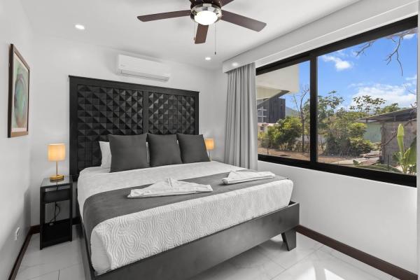 King bedroom with large window framing tropical outdoor garden views and air conditioning unit, Costa Rica