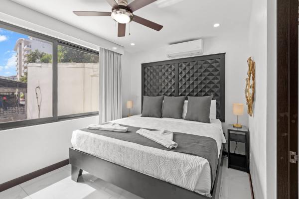 King bedroom with large street-view window, gold sunburst mirror accent and dual bedside lamps, Jaco Beach