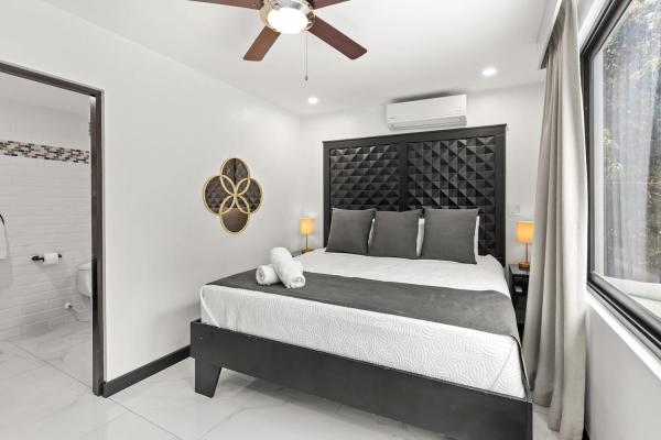 King bedroom with floor-to-ceiling window framing a lush tropical garden view and gold wall art, Costa Rica