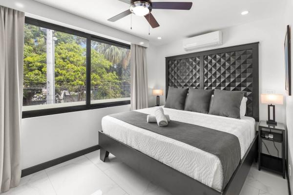 King bedroom with large garden-view window, bedside lamps and direct ensuite bathroom access, Jaco Beach