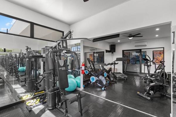 Fitness room with cable weight machine, spin bike, colorful free weights and elliptical in Jaco