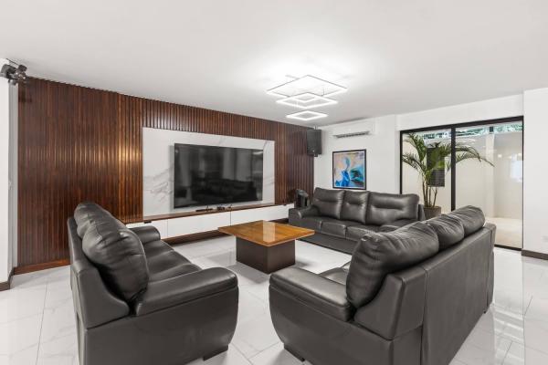 Leather sofa lounge with a distinctive wood slat accent wall and large flat screen TV, central Jaco