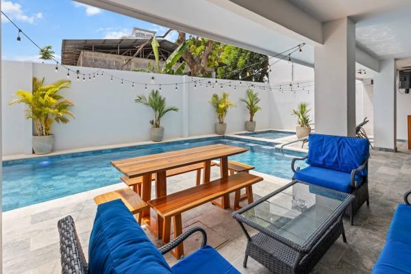 Inviting pool terrace with blue lounge chairs, rattan sofas and a picnic bench for large group gatherings
