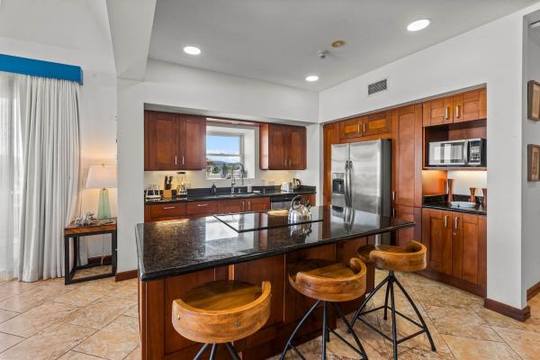 Corner kitchen view with island, wood cabinets, fridge, microwave, and small window toward the northern mountains