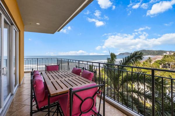 Side balcony with wood dining table and six chairs overlooking ocean and northern mountains