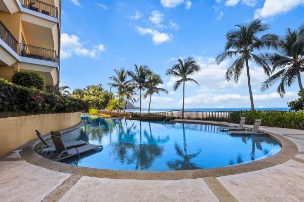 Resort pool with loungers overlooking beach, ocean, and horizon