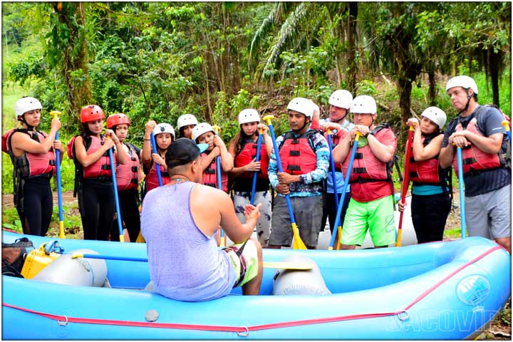 River rafting guide sitting on edge of raft and giving orientation instructions to guests