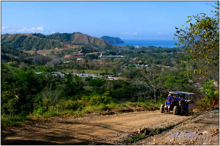 Tractor driving up mountain side with ocean view in the backgroundr